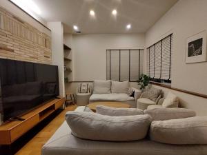 a living room with couches and a flat screen tv at マークヴィラスイート in Shimo-suwa