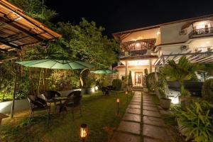 a patio with tables and umbrellas at night at The Elegant homes in Kushālnagar