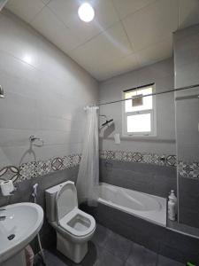 a bathroom with a toilet and a tub and a sink at Towaya studio in Al Ain
