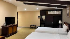a hotel room with two beds and a flat screen tv at Desert Inn Resort and Camp in Ras al Khaimah