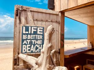 a beach shack with a sign that reads life is better at the beach at Maison huit places Piscine tennis Lacanau plage in Lacanau