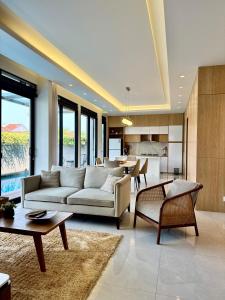 a living room with couches and tables and a kitchen at Lioravilla21 Kota Baru Parahyangan in Padalarang
