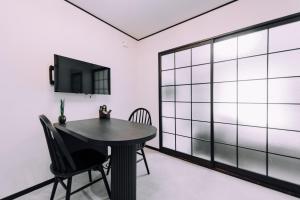 a dining room with a black table and a tv at Work Ready Stay - Quiet Nakasu 202 in Fukuoka