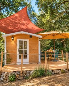 a small cabin with an orange roof and an umbrella at Roulotte nature in Salernes
