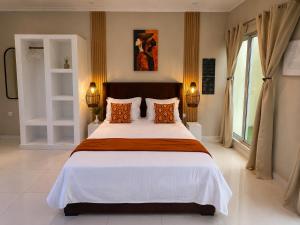 a bedroom with a large white bed with orange pillows at Lukas Garden Accra Exclusive Resort in Accra