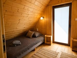a bed in a wooden room with a window at Domek Pod Tylką in Grywałd