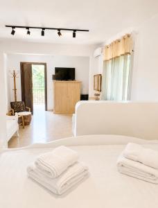 a white bedroom with white towels on a bed at Casa Boha Garden in Dhërmi