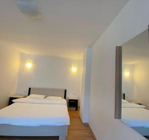 a white room with two beds and a mirror at Pensiunea CARMEN Borșa in Borşa