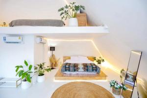 a bedroom with a bed in a room with plants at LOUVREFER in Ban Pa Pae