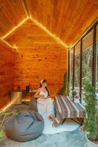 a woman sitting on a couch in a wooden room at LOUVREFER in Ban Pa Pae