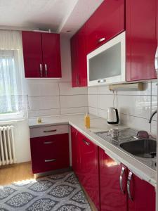 a kitchen with red cabinets and a sink at XXL apartman Free parking in Visoko
