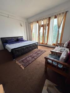 a bedroom with a bed and a couch and windows at Kepchaki Stay in Takdāh