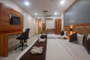 a hotel room with a bed and a desk and a television at Hotel Avion Park Executive in Mumbai