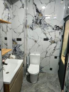 a bathroom with a white toilet and a marble wall at БорБор in Osh +24 photos