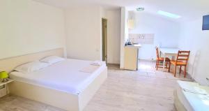 a white bedroom with a bed and a dining room at Titulescu Apartments in Bucharest