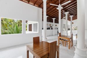 a dining room with white walls and a wooden table at Mihira Gedara Apartments in Unawatuna
