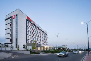 a white building on a city street with cars at Ibis Tashkent Index in Tashkent