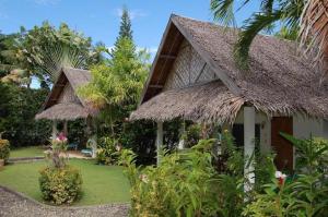 a house with a thatched roof and a garden at Marcosas Cottages Resort in Basdiot