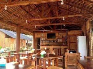 a large wooden pavilion with tables and a refrigerator at calayo beach resort in Calayo