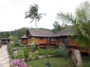 a house with a thatched roof and a palm tree at calayo beach resort in Calayo