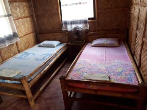 two twin beds in a room with a window at calayo beach resort in Calayo