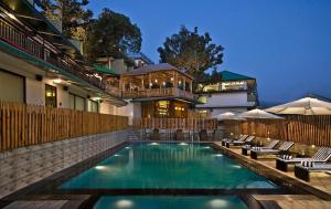 a swimming pool with chairs and a house at Fortune Park Moksha, Mcleodganj - Member ITC Hotels' Group in McLeod Ganj