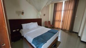 a bedroom with a large bed and two windows at Yiganda Hotel, Ethiopia in Bahir Dar