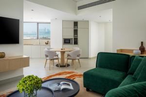 a living room with a green couch and a table at Bloom Arjaan by Rotana in Abu Dhabi
