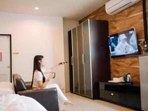 a woman sitting in a room playing a video game at Debua Mahasarakham in Maha Sarakham +75 photos