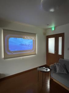 a living room with a large blue screen on the wall at Flat Dazaifu in Dazaifu