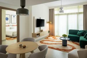 a living room with a green couch and a table at Bloom Arjaan by Rotana in Abu Dhabi
