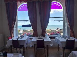 a dining room with two tables and a large window at A Maiden Rest in Weymouth