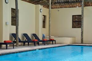 a pool with lounge chairs next to a swimming pool at Melamar Estate in Marloth Park