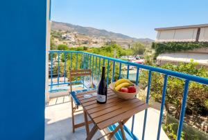 a table with a bowl of fruit and a bottle of wine on a balcony at Michele Marie apts in Agia Pelagia