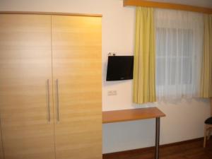 a wooden cabinet with a tv on the wall next to a window at Appartement Andi in Wagrain