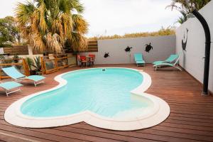 a swimming pool on a wooden deck with chairs at La case à Nath - Piscine chauffée et jacuzzi in Saint-Pierre