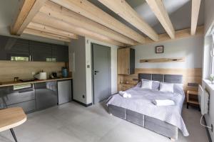 a bedroom with a large bed and a kitchen at Serce Lasu - Hotel z Duszą i Energią Kamieni in Czarna
