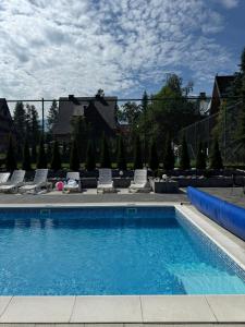 a large swimming pool with chairs and a fence at Koperkowe Domki Zakopane in Zakopane