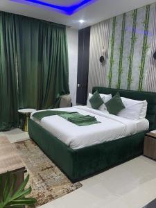 a bedroom with a large green bed with green curtains at Emirates Star Hotel & Suites in Asaba