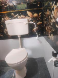 a white toilet in a bathroom with a flower wall at Sri varahi rest house in Avanigadda