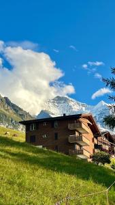 a building on a hill with a snow covered mountain at Chalet Steinbock Wengen in Wengen