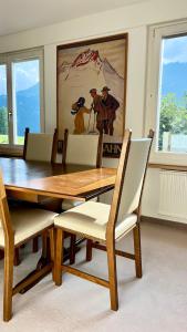 a dining room table with chairs and a painting on the wall at Chalet Steinbock Wengen in Wengen