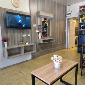 a living room with a table and a tv at Victory Place in Bangkok