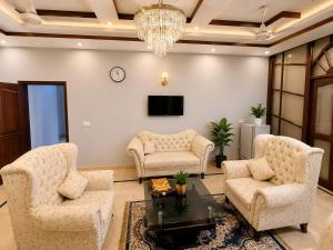 a living room with two chairs and a tv at Beach Heaven Guest House in Karachi