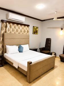 a bedroom with a large bed and a chair at Beach Heaven Guest House in Karachi