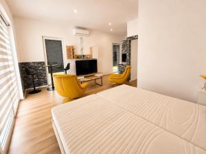 a bedroom with a large white bed and yellow chairs at Luxus Lakópark in Gárdony