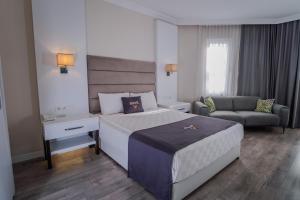 a bedroom with a bed and a couch and a chair at Siete Hotel in Antalya