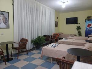 a room with two beds and tables and a tv at Roland Palaj House in Shkodër