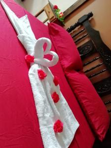 a bed with a white blanket with red flowers on it at Hospedaje del norte in Quesada