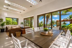 a dining room with a wooden table and white chairs at Casa Seven Ocean Front with Private C hef Included in Isla Mujeres